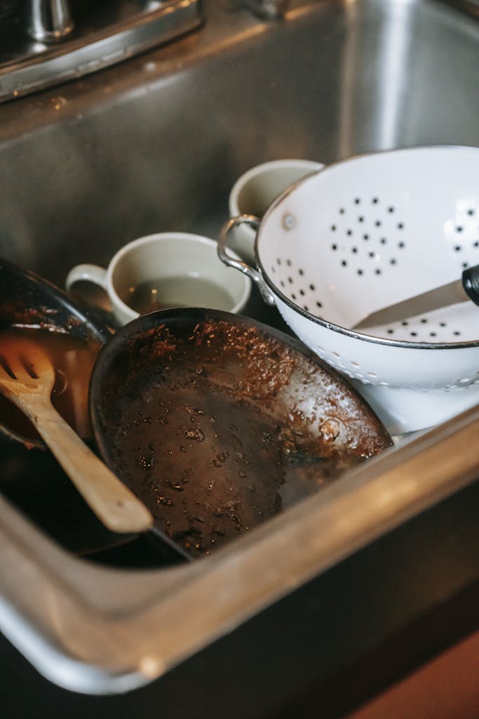 High angle heap of dirty dishes placed in sink after cooking in kitchen